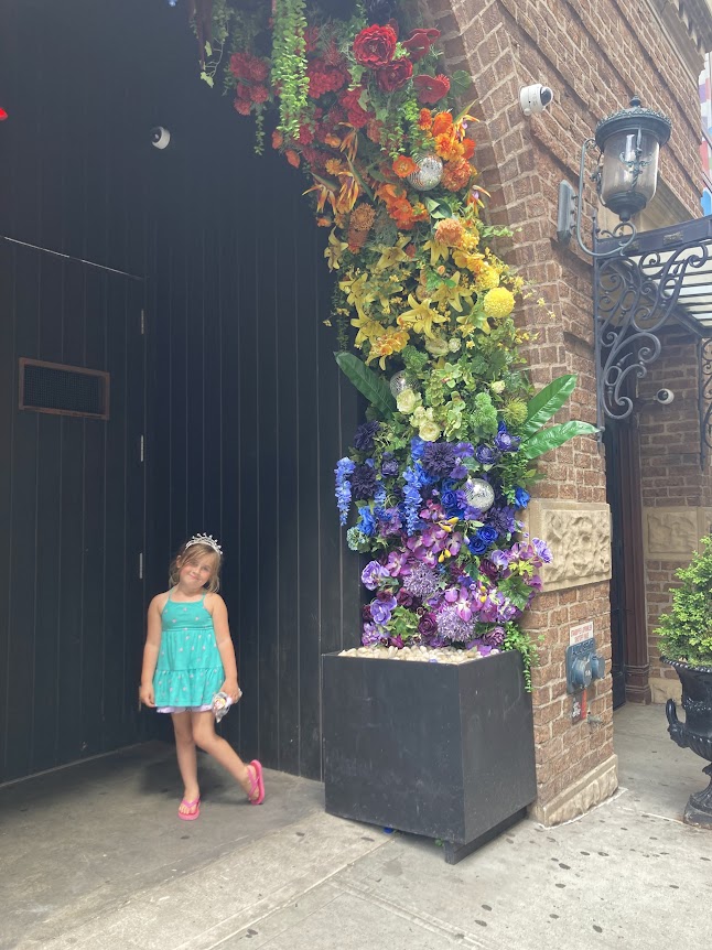 rainbow color flower arch with child in nyc for pride month