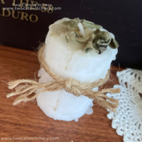 White votive candle with sage on top