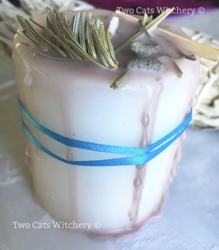 White candle with herbs on top